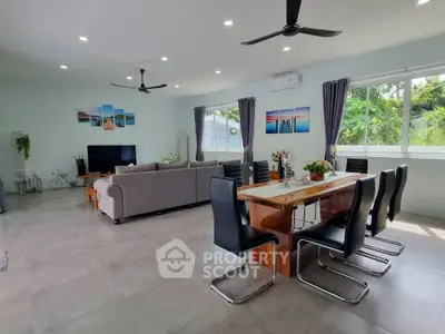 Spacious modern living room with dining area, large windows, and stylish decor in a serene setting.