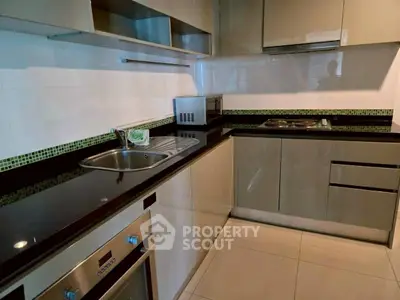 Modern kitchen with sleek cabinets and built-in appliances, featuring a stylish black countertop.