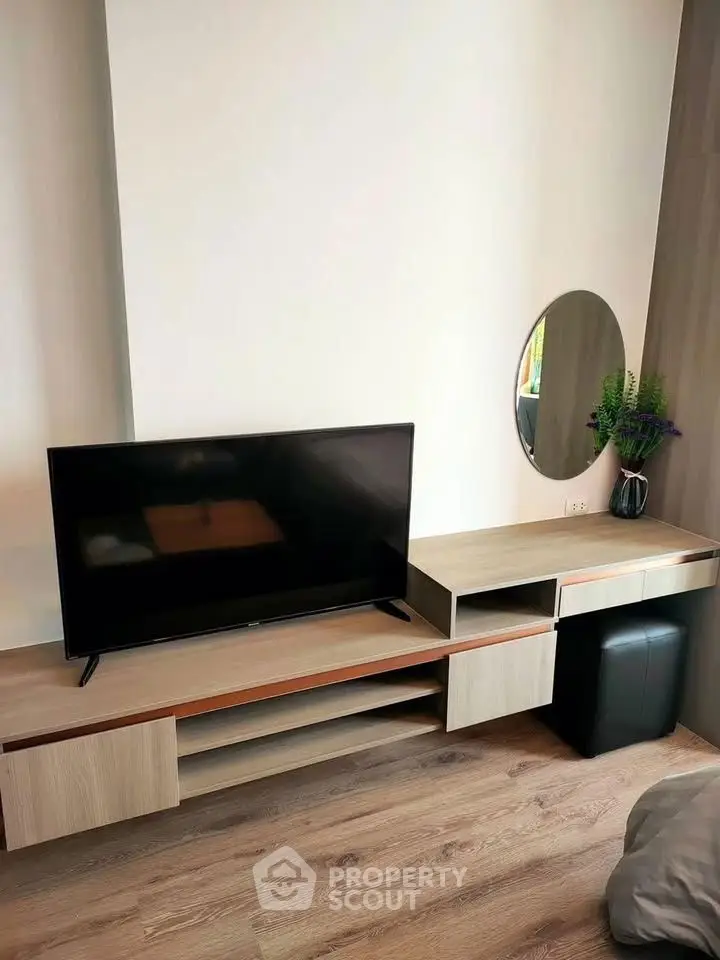 Modern living room with sleek TV stand and round mirror, featuring stylish wooden flooring.