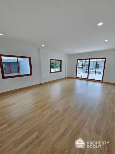 Spacious living room with gleaming hardwood floors, abundant natural light, and a modern, airy ambiance, perfect for entertaining or relaxation.