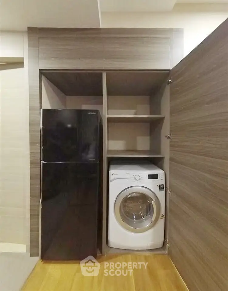 Modern kitchen with sleek black fridge and washing machine in compact storage space.