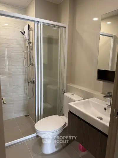 Modern bathroom with glass shower enclosure and sleek fixtures in a contemporary apartment.