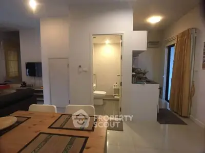 Cozy open-plan living area with dining table and view into a modern bathroom.