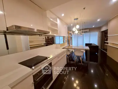 Modern kitchen with sleek design and open layout, featuring stylish lighting and glossy black flooring.
