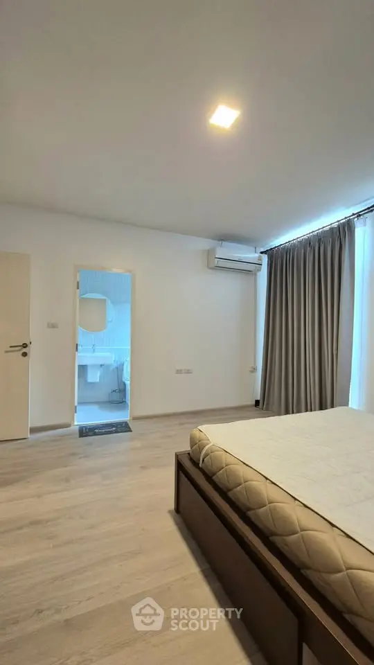 Spacious bedroom with modern design and ensuite bathroom, featuring sleek flooring and ample natural light.