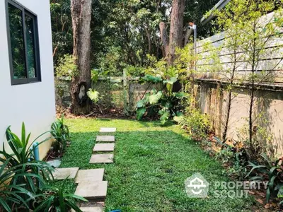 Charming garden with lush greenery and stone pathway in serene residential area.