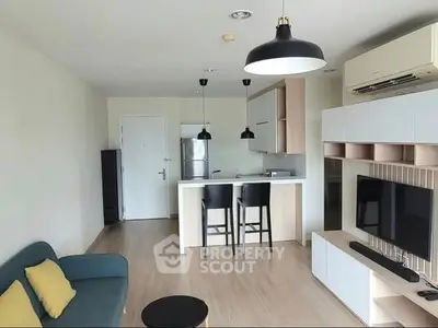 Modern open-plan living room with kitchen, featuring sleek furniture and stylish lighting.