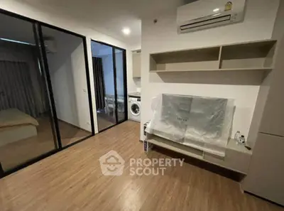 Modern apartment interior with wooden flooring and sliding glass doors, featuring a washing machine and air conditioning.