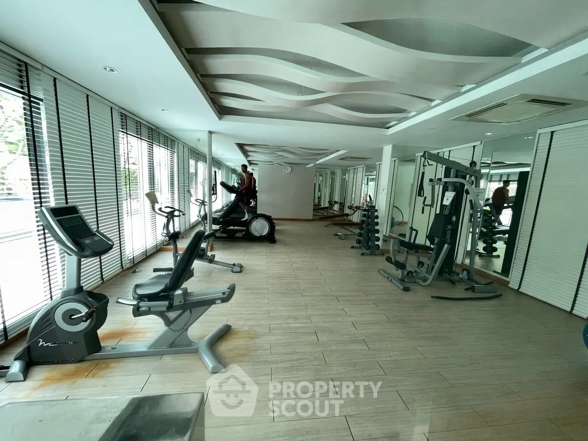 Spacious modern gym with state-of-the-art fitness equipment and stylish interior design.