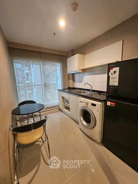 Modern kitchen with washing machine and dining area in a compact apartment