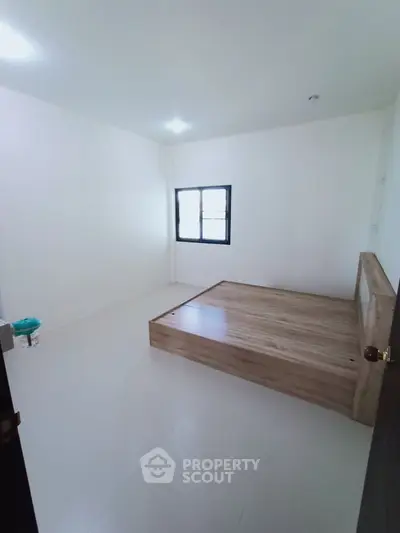 Minimalist bedroom with wooden platform bed and white walls