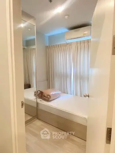 Cozy bedroom with mirrored closet and air conditioning in modern apartment.