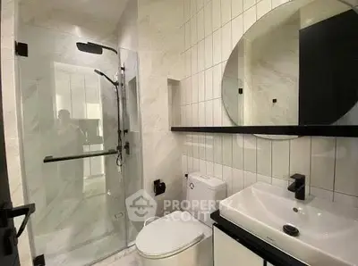 Modern bathroom with glass shower, sleek fixtures, and elegant tile design.