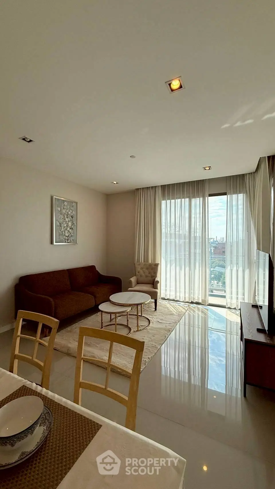 Spacious living room with modern furniture and large windows offering city views.
