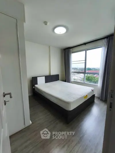 Spacious bedroom with large window offering a scenic view, featuring modern furnishings and sleek flooring.