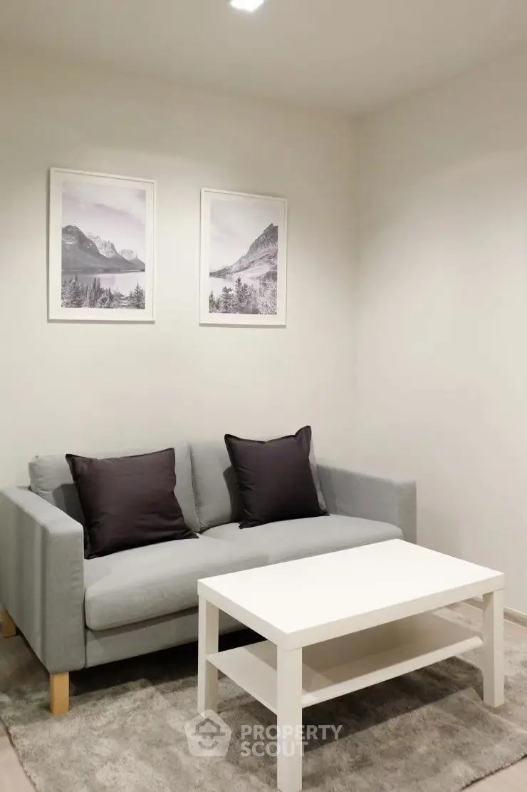 Cozy living room with modern gray sofa and white coffee table, accented by mountain artwork.