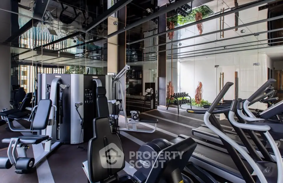 Luxurious gym with modern equipment and mirrored walls in upscale residential building.