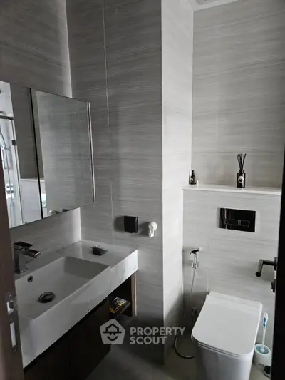Modern bathroom with sleek design, featuring a large mirror, stylish sink, and contemporary fixtures.
