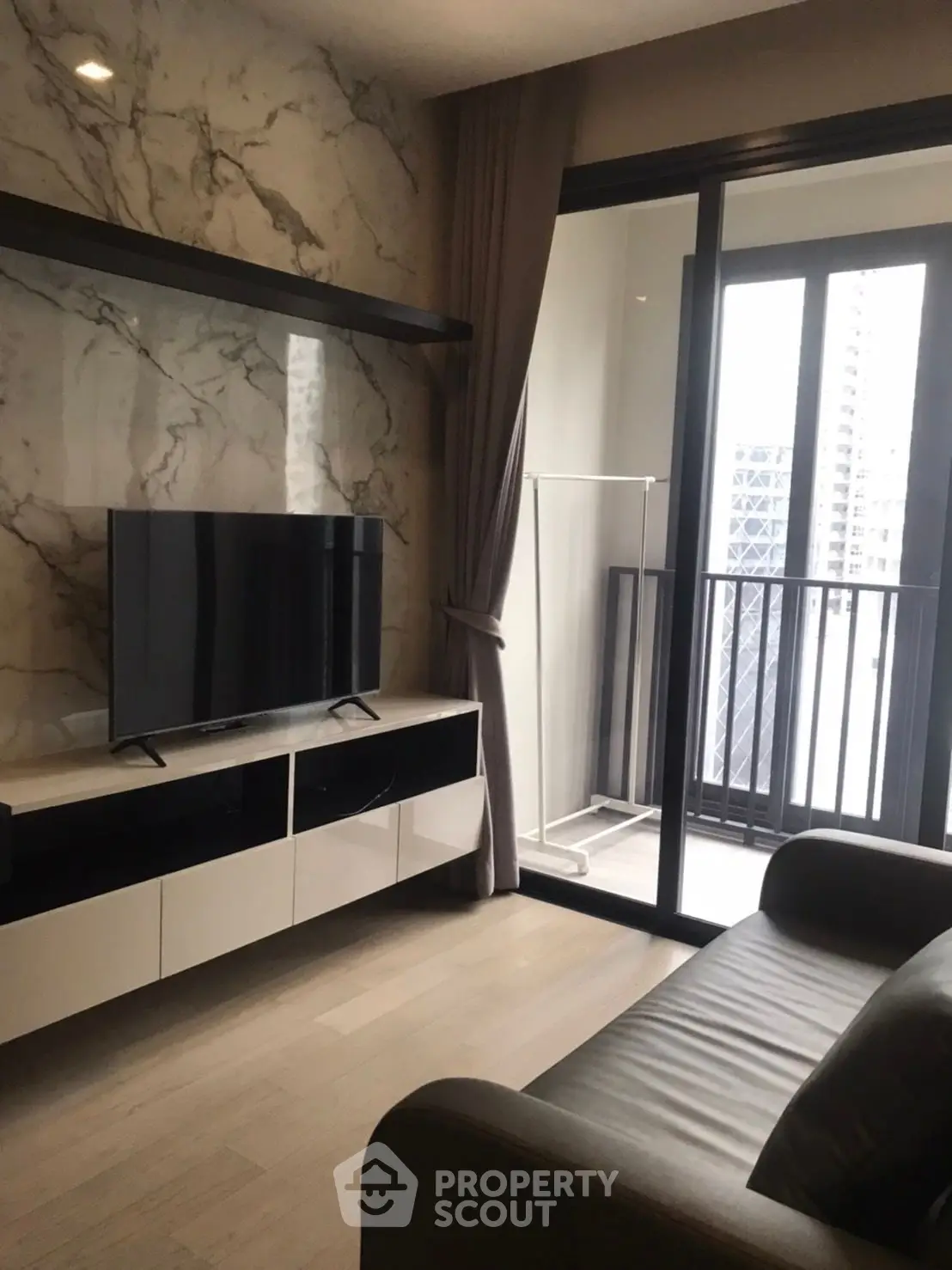 Modern living room with marble accent wall and balcony view in luxury apartment