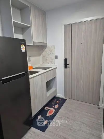Compact modern kitchen with sleek cabinetry and stainless steel fridge
