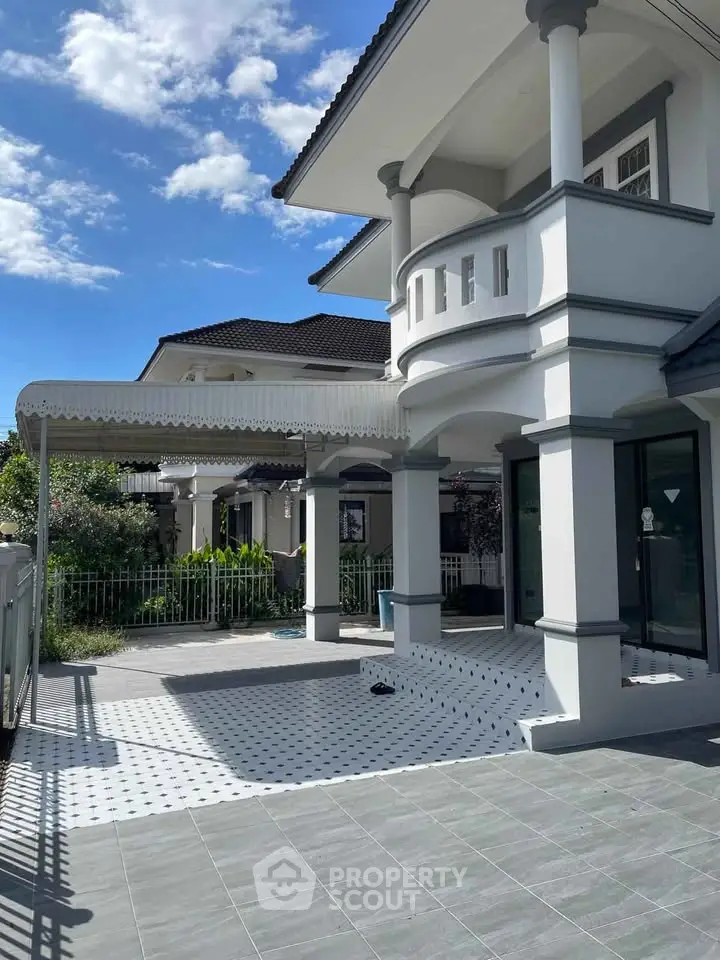 Elegant two-story house with spacious patio and modern design under clear blue sky.