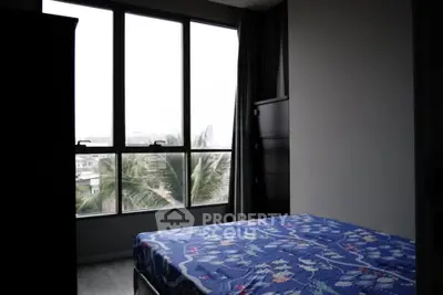 Cozy bedroom with large windows offering a serene view of palm trees and cityscape.