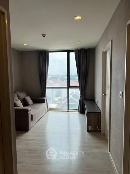 Modern living room with large window and cozy sofa, offering a bright and inviting atmosphere.