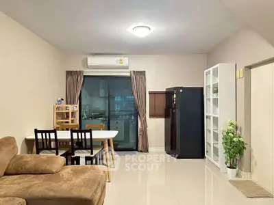 Modern living room with dining area and kitchen view, featuring sleek furniture and neutral tones.
