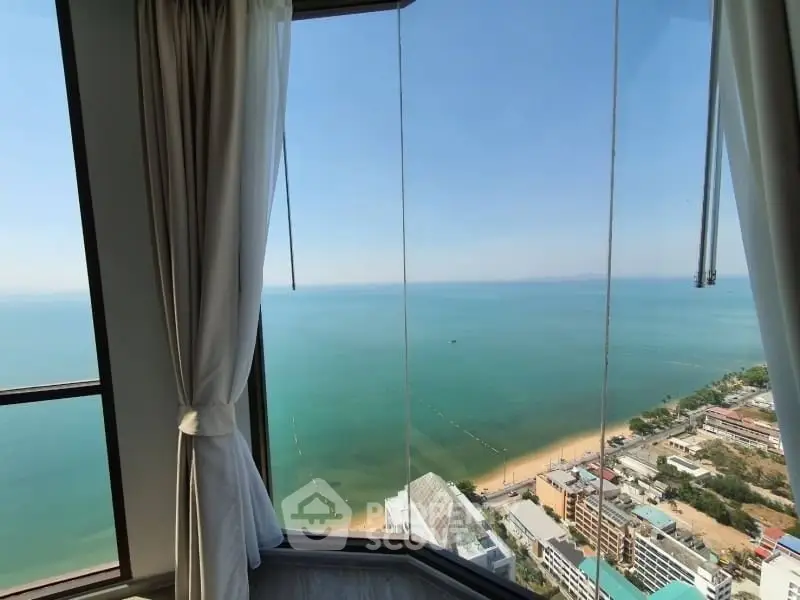 Stunning ocean view from high-rise apartment window with elegant curtains