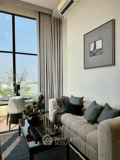 Modern living room with large windows and city view, featuring stylish furniture and decor.
