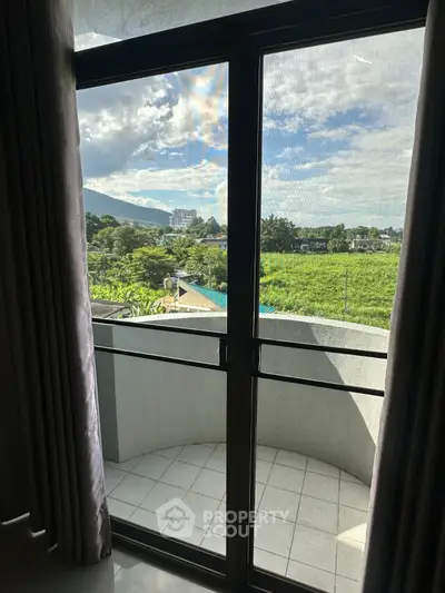Scenic view from a balcony with lush greenery and mountains in the background.