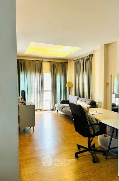 Spacious living room with modern decor and natural light, featuring a cozy sofa and work desk.