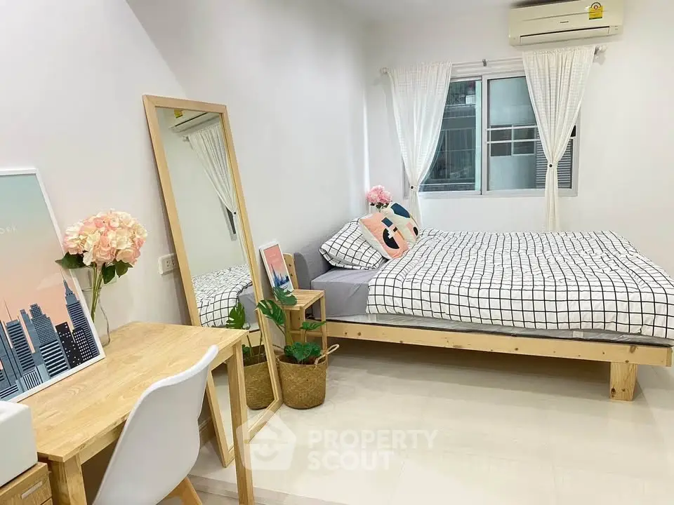 Modern bedroom with stylish decor, featuring a cozy bed, desk, and large mirror, perfect for urban living.