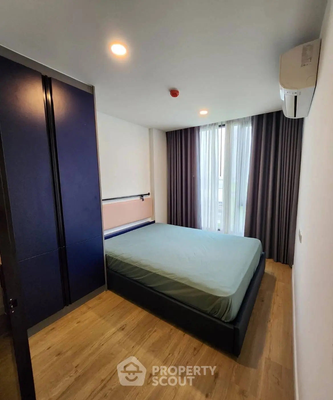Modern bedroom with large window and minimalist design, featuring a comfortable bed and sleek wooden flooring.