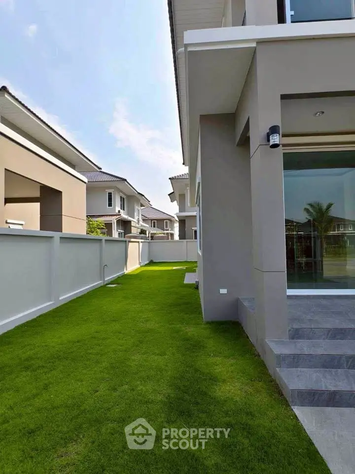 Modern house exterior with lush green lawn and sleek architectural design.