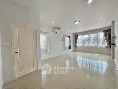 Spacious and bright living room with large windows and modern air conditioning unit.