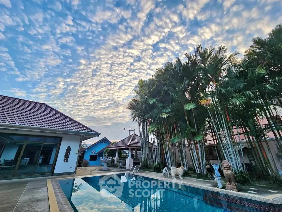 Stunning tropical villa with pool and lush palm trees under a picturesque sky.