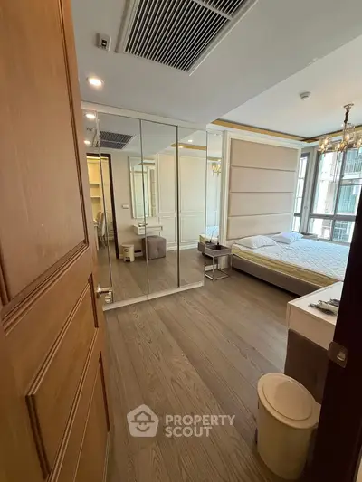 Spacious bedroom with mirrored closet and elegant chandelier in modern apartment