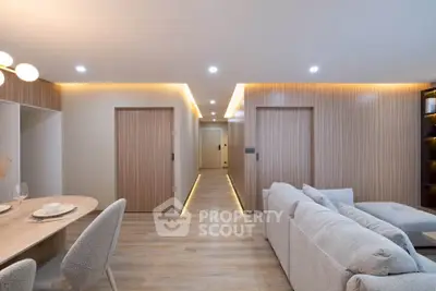 Modern living room with cozy seating and elegant dining area, featuring warm lighting and wooden accents.