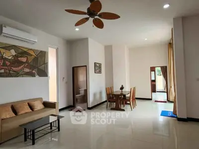 Spacious living room with modern decor and dining area, featuring elegant ceiling fan.