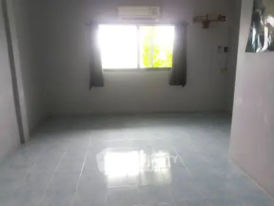 Spacious empty room with tiled floor and large window, ideal for customization.