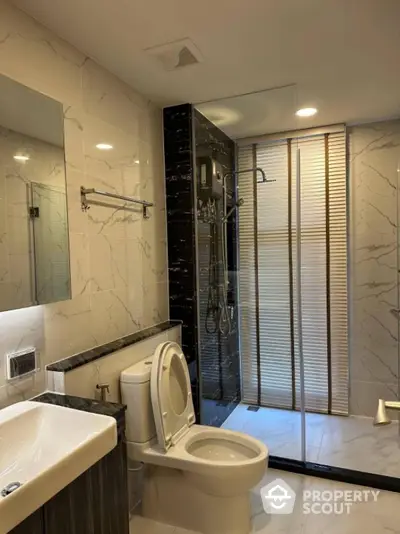 Modern bathroom with glass shower, marble tiles, and sleek fixtures