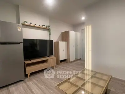Modern living room with sleek furniture and flat-screen TV, featuring a stylish wooden floor and minimalist decor.