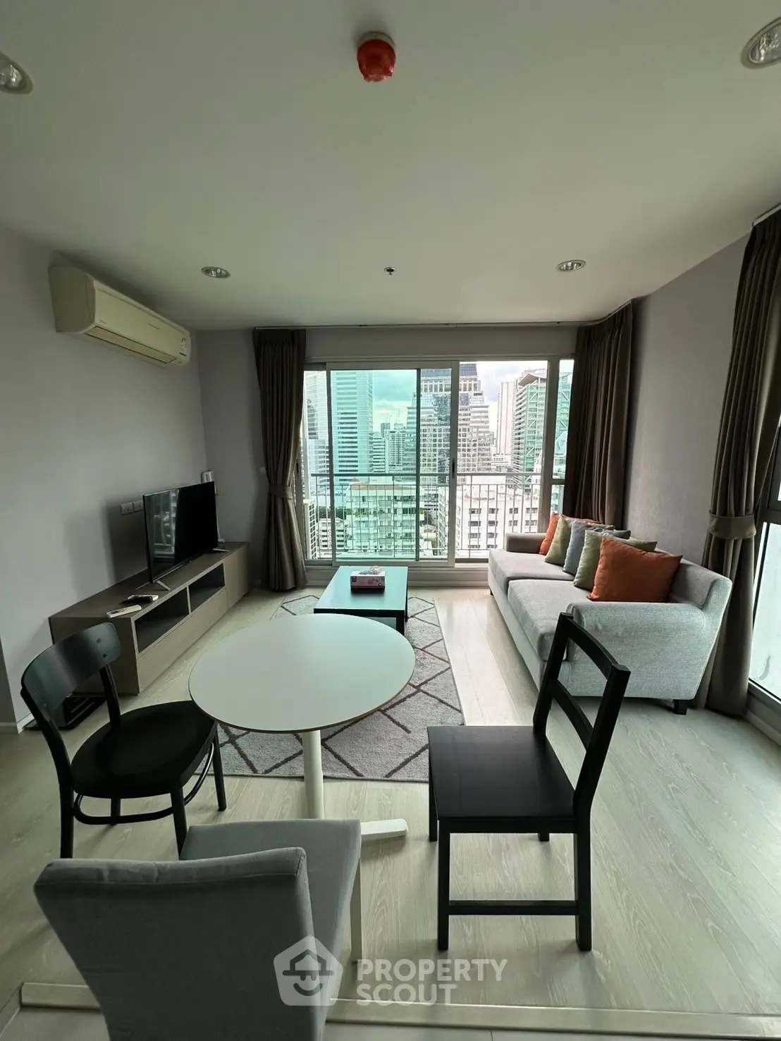 Modern living room with city view, stylish furniture, and large windows in high-rise apartment.