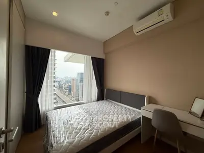 Modern bedroom with city view, featuring a large window, air conditioning, and a sleek desk.