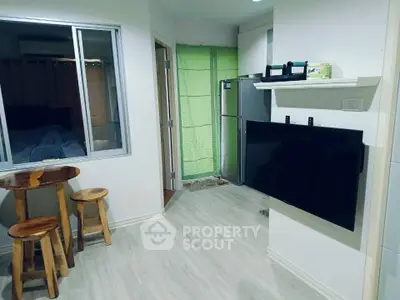 Cozy apartment interior with modern kitchen and dining area, featuring a wall-mounted TV and stylish wooden stools.