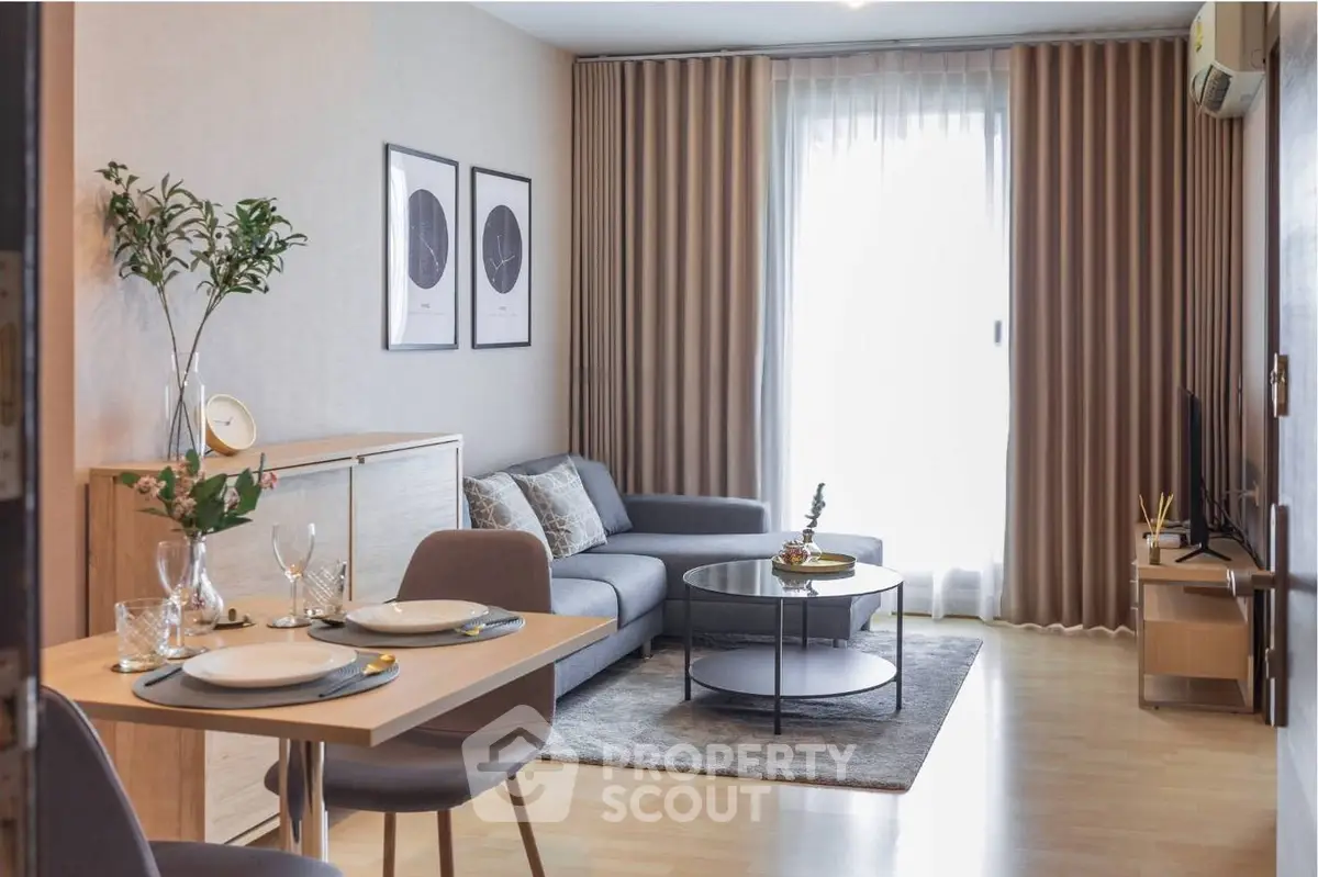 Modern living room with stylish decor, cozy seating, and natural light from large window.