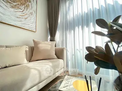 Elegant living room with plush sofa, large window, and stylish decor, perfect for relaxation and entertaining.