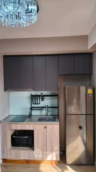 Modern compact kitchen with stainless steel fridge and sleek cabinetry