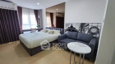 Modern studio apartment with cozy bed and stylish sofa in open layout.